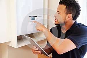 Technician servicing boilerÂ holding tablet computer